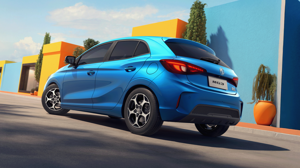 MG3 in Como Blue, im Hintergrund gelbe und hellblaue Gebäude, Ansicht von seitlich hinten